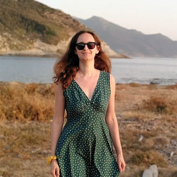 A long haired woman is wearing the Lune dress as a prom dress sewing pattern. She is walking outside in a stunning landscape looking like Scotland's lochs.