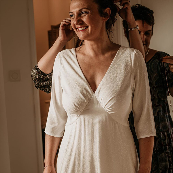 The Lune dress is shown here as a wedding dress sewing pattern. The bride is modeling it in an ivory textured fabric. She chose the long sleeve option.
