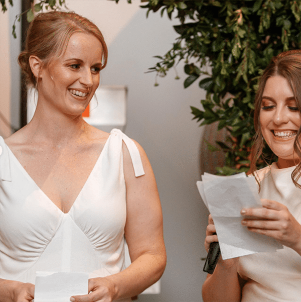 A young blonde woman wears the Lune dress. She chose it as a bridesmaids dress sewing pattern. She is wearing the dress in a white crepe with shoulder ties.